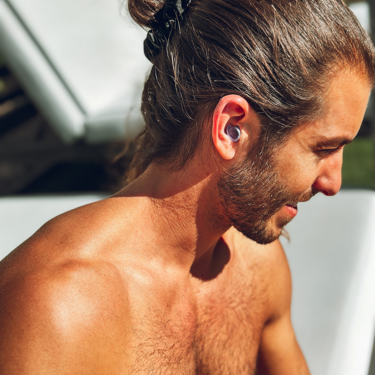 un homme regardant vers le bas avec des bouchons d'oreilles watersafe insérés