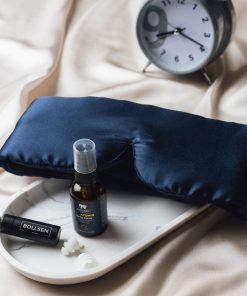 Un spray de sommeil, un masque et des bouchons d'oreille sont posés sur le lit